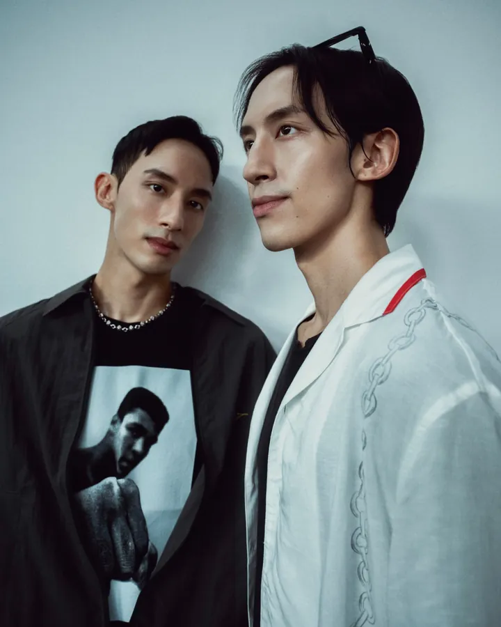 Julien and Brandon Leo, the twin brothers who founded FRSHOFF, side by side against a pale wall: one in black, one in white with a single red stripe at the collar.